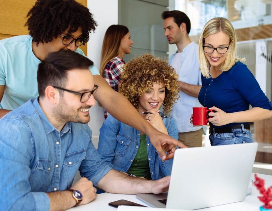 Group of employees reviewing content together on a laptop.